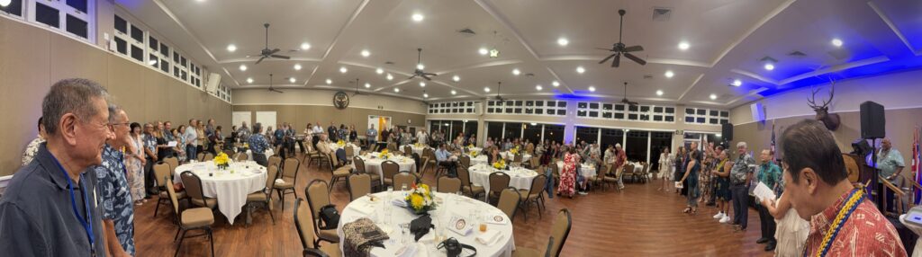 Panorama of people standing around the perimeter of the banquet room